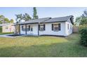 White brick ranch house with gray roof, and a green lawn at 18 Wildwood Dr, Edgewater, FL 32132