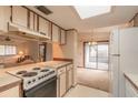 Kitchen with light-colored cabinets, a stove, and access to a back patio at 1820 Sabal Palm Dr, Edgewater, FL 32132