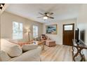 Cozy living room with light wood floors, bright windows, ceiling fan, and striped couch and armchair at 388 N Glencoe Rd, New Smyrna Beach, FL 32168