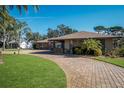 Brick ranch house with paver driveway and palm trees at 803 Silk Oak Ct, New Smyrna Beach, FL 32168