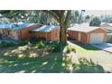 Exterior view of home with a detached garage, mature trees, and green lawn at 1202 12Th St, Edgewater, FL 32132