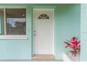 White front door with a semicircular window and a red plant beside it at 211 Maurice Ave, New Smyrna Beach, FL 32168