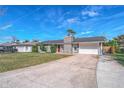 Gray house with red door, stone chimney, and attached garage. Long driveway at 2507 Milton Ave, New Smyrna Beach, FL 32168