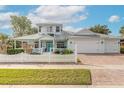 Two-story light teal home with a large driveway, white picket fence, and mature landscaping at 2817 Bay Side Dr, New Smyrna Beach, FL 32168