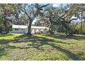 White home with a green roof, situated on a large lot with mature trees at 384 W Ariel Rd, Edgewater, FL 32141