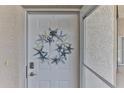 Front door adorned with a starfish wreath, complemented by a white door and textured wall at 432 Bouchelle Dr # 403, New Smyrna Beach, FL 32169