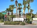 Entrance to Venetian Villas featuring lush landscaping and palm trees, offering a serene and welcoming atmosphere at 113 Lagoon Ct, New Smyrna Beach, FL 32169