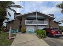 Charming townhouse with brick facade, balcony, and attached garage, complemented by lush landscaping and welcoming outdoor seating at 113 Lagoon Ct, New Smyrna Beach, FL 32169