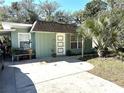 Light green house with white door, driveway, and landscaping at 1506 Palmetto St, New Smyrna Beach, FL 32168