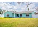 Light teal single story home with a large yard and white fence at 2720 Queen Palm Dr, Edgewater, FL 32141