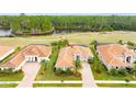 Aerial view of home with brick driveway, tile roof, and lush landscaping near the golf course at 2824 S Asciano Ct, New Smyrna Beach, FL 32168