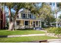 Two-story yellow house with a wraparound porch and a large tree in the front yard at 608 Magnolia St, New Smyrna Beach, FL 32168