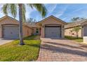 Front view of tan house with gray garage doors and landscaping at 108 Tuscany Villas Dr # 15, Edgewater, FL 32141