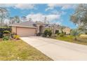 Tan house exterior with a two-car garage and landscaped front yard at 1155 Kilkenny Ln, Ormond Beach, FL 32174