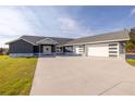 Modern home with gray siding, stone accents, and a three-car garage at 18459 Sw 66Th Loop, Dunnellon, FL 34432