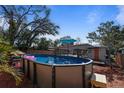 Backyard featuring an above-ground pool, wooden deck, shed, and mature trees under a blue sky at 229 Columbus Ave, Daytona Beach, FL 32118