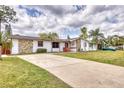 Attractive single-story home with a long driveway, unique stone accents, and a spacious front lawn at 2712 Queen Palm Dr, Edgewater, FL 32141