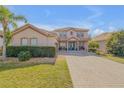 Beautiful two-story home with a well-manicured lawn, paver driveway and quaint front porch at 454 Venetian Villa Dr, New Smyrna Beach, FL 32168