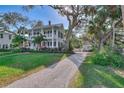 Two-story light blue house with red door, gravel driveway, and mature trees at 504 N Riverside Dr, New Smyrna Beach, FL 32168