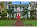 Two-story light blue house with red door, landscaping, and brick pathway at 504 N Riverside Dr, New Smyrna Beach, FL 32168