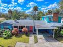 Exterior view of a home with a red door, well-maintained lawn, and a convenient covered carport at 634 N Riverside Dr, New Smyrna Beach, FL 32168