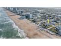 Coastal view of a charming white beach cottage flanked by palm trees near the sandy shoreline and ocean at 8 Ocean Dr, Ormond Beach, FL 32176