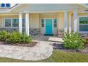 Inviting front porch with light-colored siding, blue door, and a brick walkway at 91 Maura Ter, Ponce Inlet, FL 32127