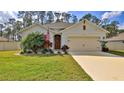 Inviting single-story home features manicured lawn, lush landscaping, and a convenient attached two-car garage at 114 Sunset Point Dr, Ormond Beach, FL 32174