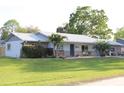 Single story home with brick and siding, metal roof, mature trees, and long driveway leading to a one car garage at 2404 Victory Palm Dr, Edgewater, FL 32141