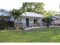 Single story home with brick and siding, metal roof, mature trees, and long driveway leading to a one car garage at 2404 Victory Palm Dr, Edgewater, FL 32141