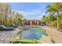 Resort-style backyard oasis featuring a sparkling pool, hot tub, tiki bar, and ample lounge space for entertaining at 308 Normandy Ave, New Smyrna Beach, FL 32169
