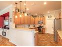 Well-lit kitchen featuring wooden cabinets, stainless steel appliances, and a cozy breakfast bar at 3456 Pegaso Ave, New Smyrna Beach, FL 32168