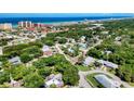 Neighborhood aerial view with lush trees and the ocean and beach in the distance at 3800 Saxon Dr # 250, New Smyrna Beach, FL 32169