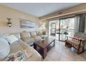 Cozy living room featuring a comfortable sofa, coffee table, and access to a balcony with outdoor seating at 3800 Saxon Dr # 250, New Smyrna Beach, FL 32169