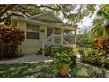Charming, light yellow home with a cozy front porch surrounded by lush, tropical landscaping and mature trees at 4426 Saxon Dr, New Smyrna Beach, FL 32169