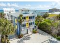 Coastal home featuring palm trees, yellow accents, white railings and a three-car garage near the ocean at 6531 Turtlemound Rd, New Smyrna Beach, FL 32169