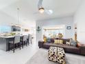 Open-concept living room featuring kitchen view, couch with decorative pillows and an overhead ceiling fan at 751 Pine Shores Cir, New Smyrna Beach, FL 32168
