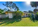 Landscaped front yard with vibrant green grass, palm trees and a glimpse of the home's facade at 1043 Beulah Dr, Edgewater, FL 32132