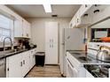 Galley kitchen features white cabinets, black countertops, stainless steel sink and wood-look flooring at 1140 Fairvilla Dr, New Smyrna Beach, FL 32168