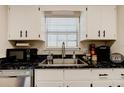 Updated kitchen features white cabinets, dark countertops and a stainless steel sink under window at 1140 Fairvilla Dr, New Smyrna Beach, FL 32168