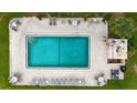 Aerial view of community pool with lounge chairs, tables, and lush green surroundings at 144 S Halifax Ave # 26, Daytona Beach, FL 32118