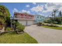 Two-story home with a two-car garage, salmon exterior, a lush green lawn and blue sky with white clouds at 6443 Engram Rd, New Smyrna Beach, FL 32169