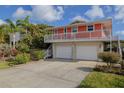 Charming exterior of a raised beach house featuring a two-car garage and ample parking at 6443 Engram Rd, New Smyrna Beach, FL 32169