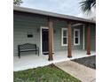 Covered front porch with stained columns and a black front door, with landscaping at 956 Tall Pine Dr, Port Orange, FL 32127