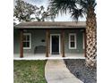 Inviting front porch with stained columns, a black front door, a bench and nice landscaping at 956 Tall Pine Dr, Port Orange, FL 32127
