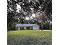 Beautiful single-story home with a well-manicured lawn, mature trees, and a two-car garage at 2380 Captain Butler Trl, New Smyrna Beach, FL 32168