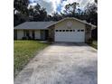 Well-maintained single-story home with stone accents, a two-car garage, and a paved driveway at 2380 Captain Butler Trl, New Smyrna Beach, FL 32168