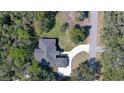 Birds-eye view of a home with dark roof, light colored circular driveway, and lush surrounding greenery at 1350 Scarlett Trl, New Smyrna Beach, FL 32168
