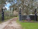 Private gated horse farm entrance with a wooden fence and landscaping creating a welcoming and secure approach at 1715 Fern Park Dr, Port Orange, FL 32128