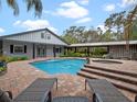 Resort-style pool with brick patio, hot tub, and lush landscaping surrounding the backyard oasis at 1715 Fern Park Dr, Port Orange, FL 32128